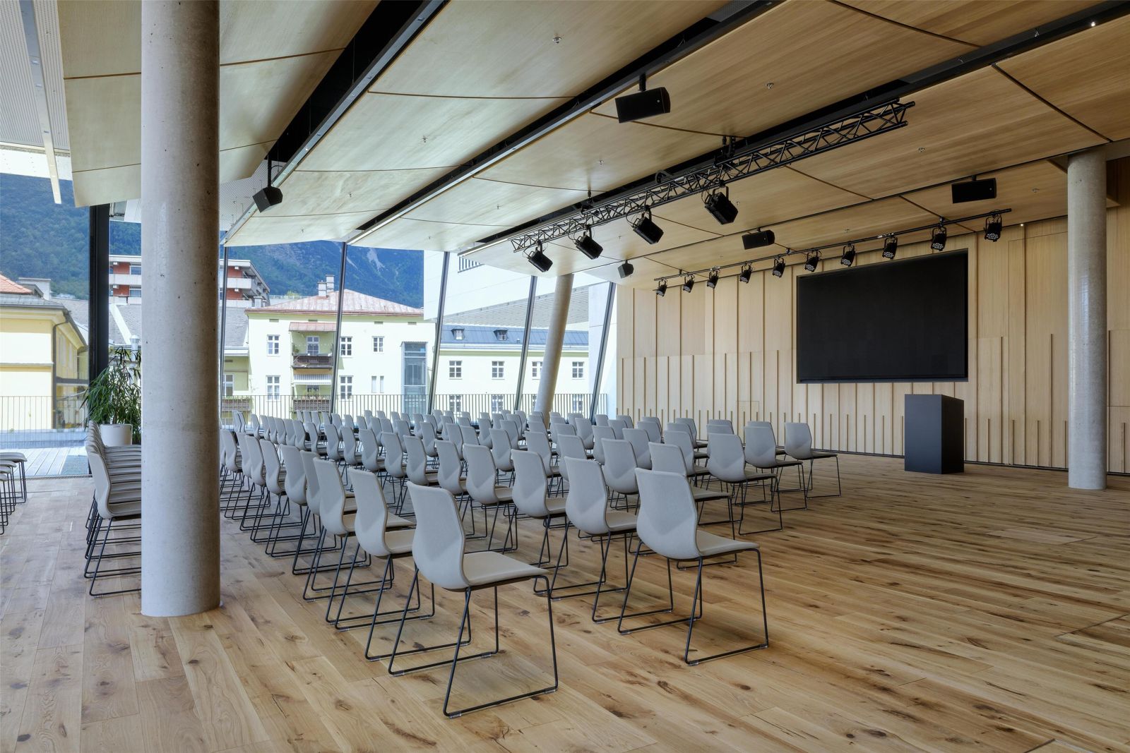 Saal Friedrich mit Stuhlreihen, Holzdecke und Glasfront mit Blick auf die Berge